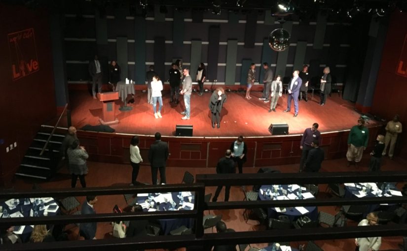 Grainy photo of actor Anna Deveare Smith on a stage with other scattered around.